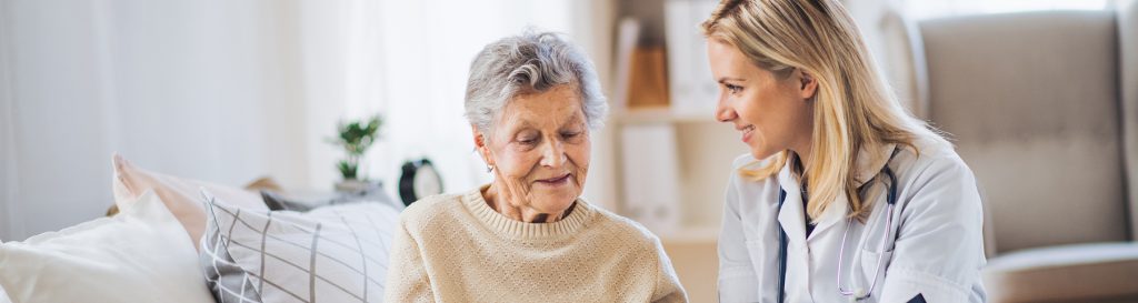 Young health service woman showing senior woman how to take pills
