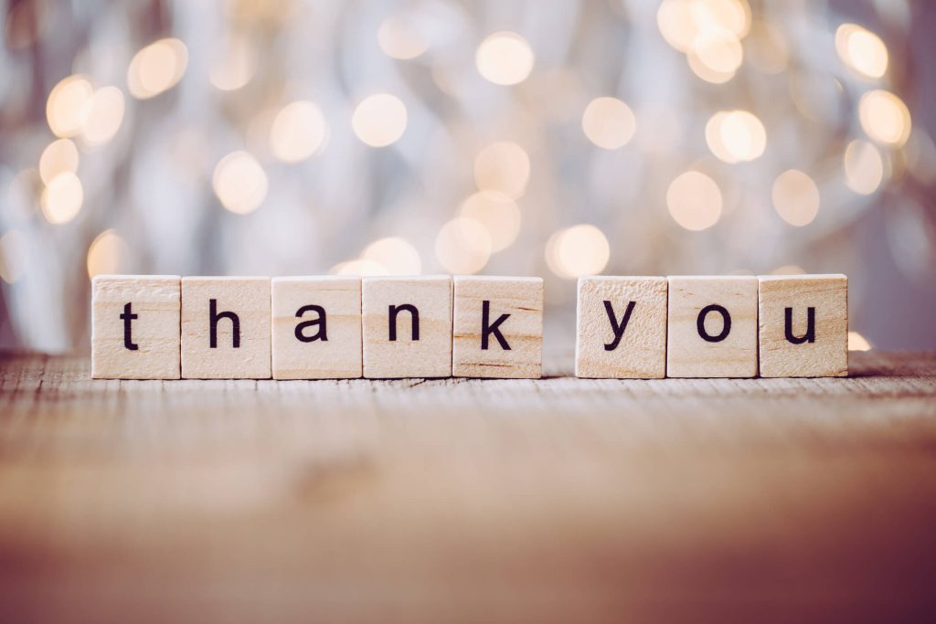 thank you spelled on scrabble letters in front of christmas lights