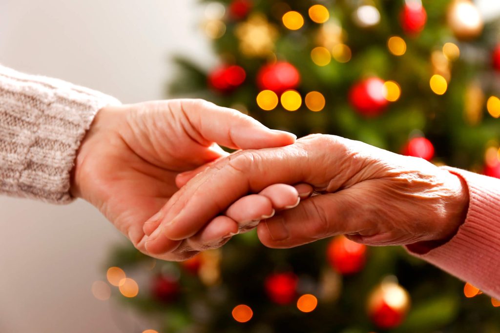 Seniors holding hands in front of christmas tree