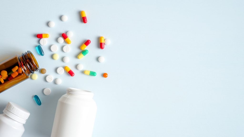 Medicine bottles with spilled medicine spread out on backdrop