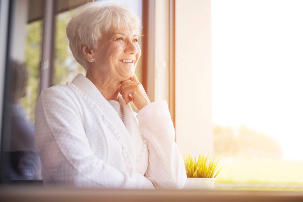 Senior woman staring out window smiling