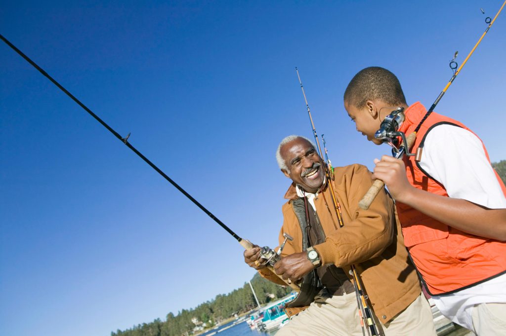 Grandfather and son holding fishing rods in a boat