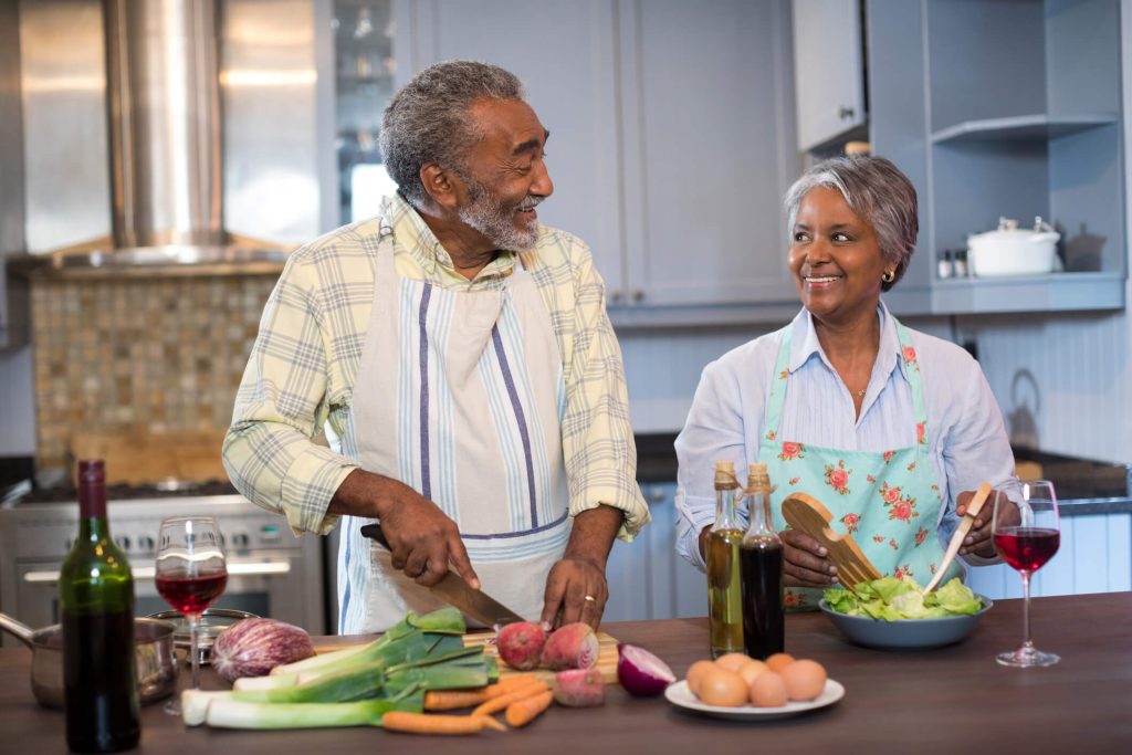 miling couple talking while preparing food in kitchen at home