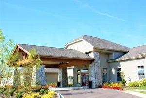 Single-story building with stone and siding exterior, covered entrance, landscaping, and a clear blue sky.