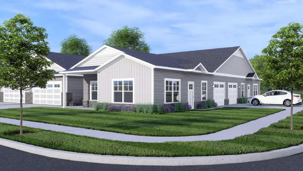 A modern single-story building with a gray exterior, surrounded by green grass and trees, featuring a driveway and parked car.