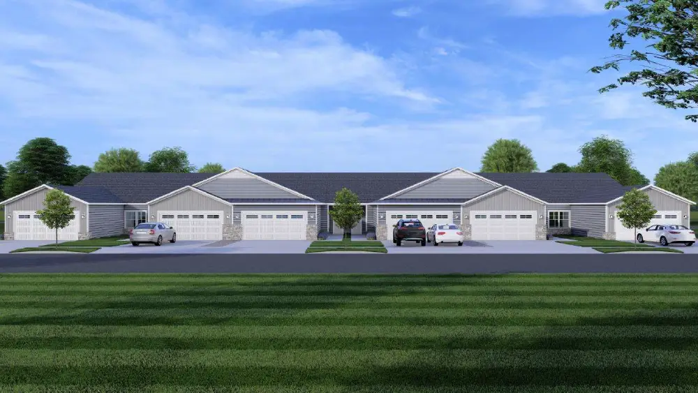 A row of modern single-story homes with garages, set against a green lawn and blue sky.